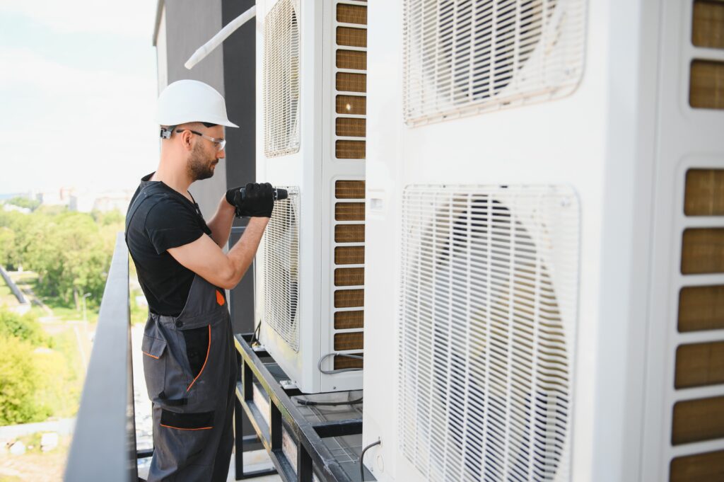 Young man repairman checking an outside air conditioner unit.